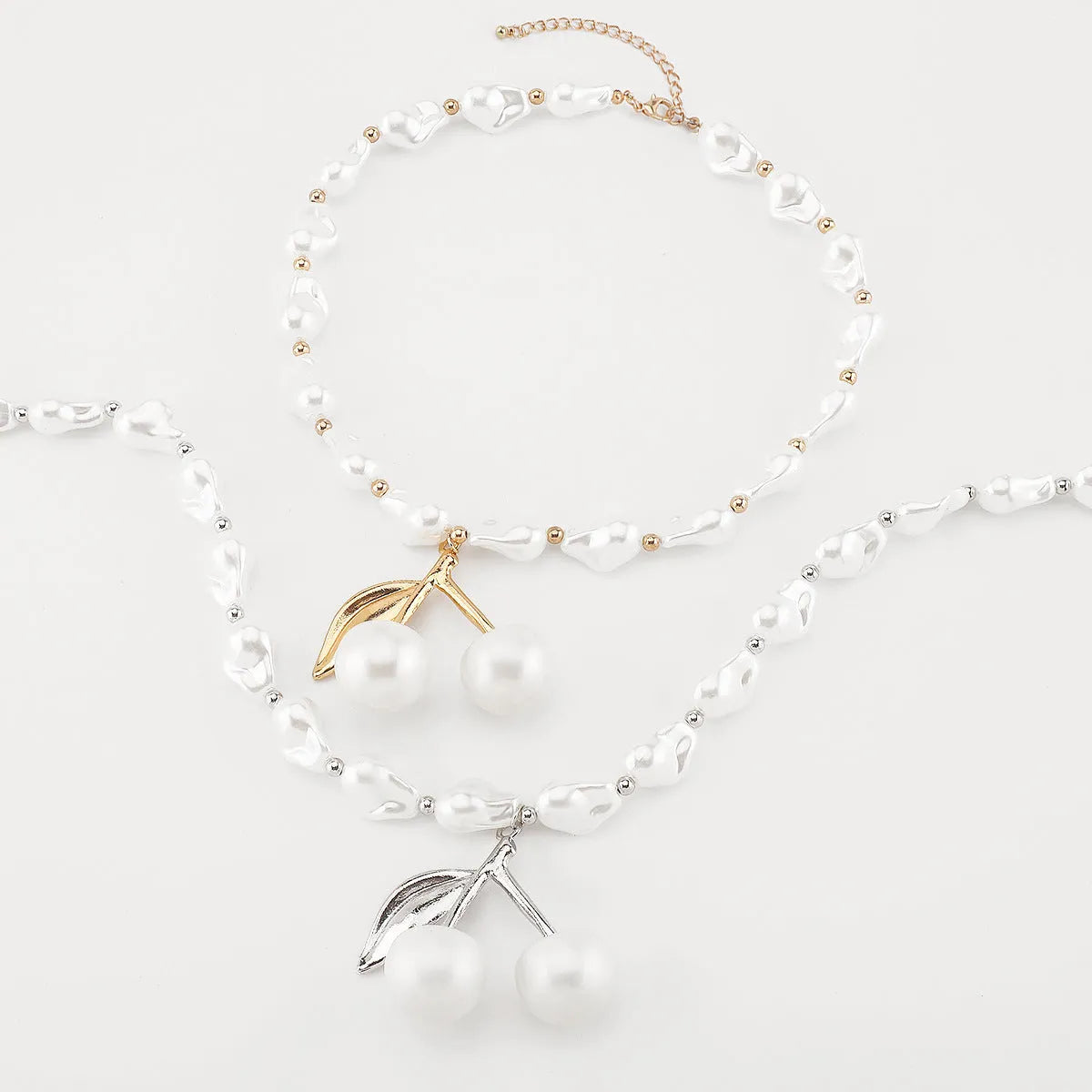 Gold geometric cherry fruit pendant on an adjustable white imitation pearl chain necklace.