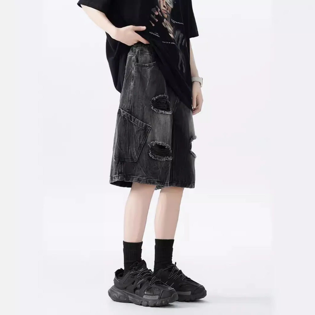 Man wearing loose-fit black denim shorts with ripped detailing and a washed vintage finish.