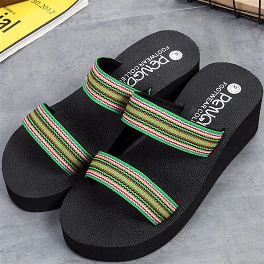 Women's brown bohemian sliders with elastic strap and rubber sole on a wooden floor.