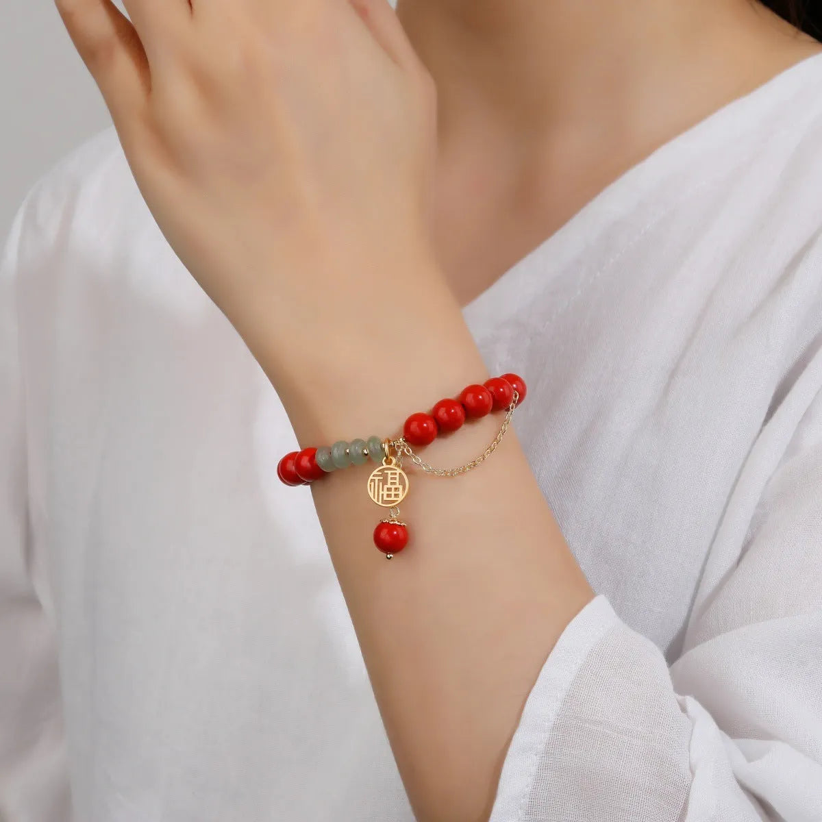 Handcrafted red sand cinnabar bracelet with fu character charm, jade spacer beads, and tassel decoration