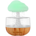 White cloud-shaped humidifier with multi-colour night light and essential oil diffuser on a table.