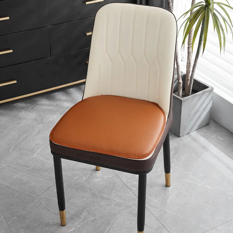 Leather horseshoe-shaped seat cushion in orange colour on dining chair