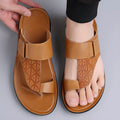 Men's white cowhide open-toe beach slippers with a rubber sole on a sandy background.