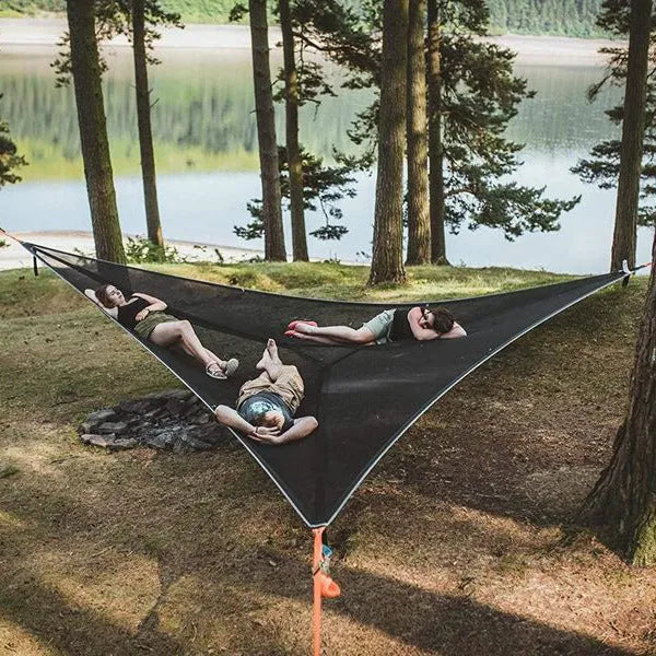 Folding portable mesh hammock in black, set up outdoors, with three supporting straps
