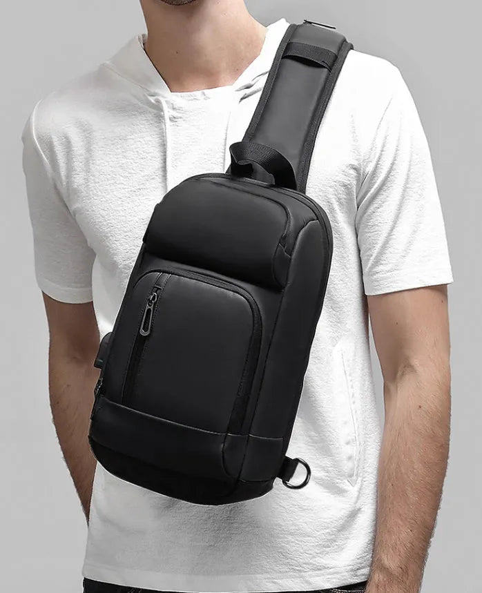 Black medium-sized PVC outdoor shoulder bag with an air cushion strap and internal organiser pockets.