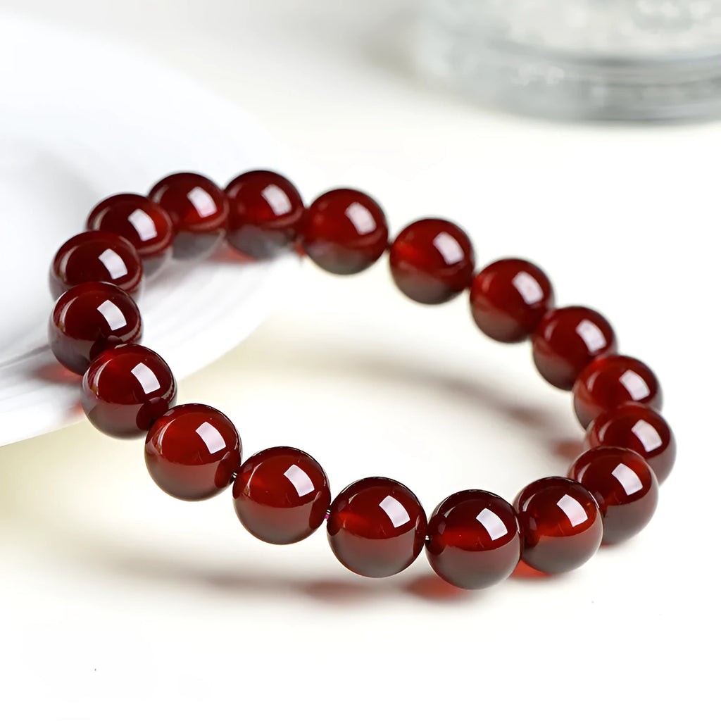 Natural orange red garnet ball bracelet with a traditional Ruyi-style clasp on a wrist.