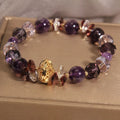 Purple crystal bracelet with pumpkin beads and a wind chimes charm on wrist.