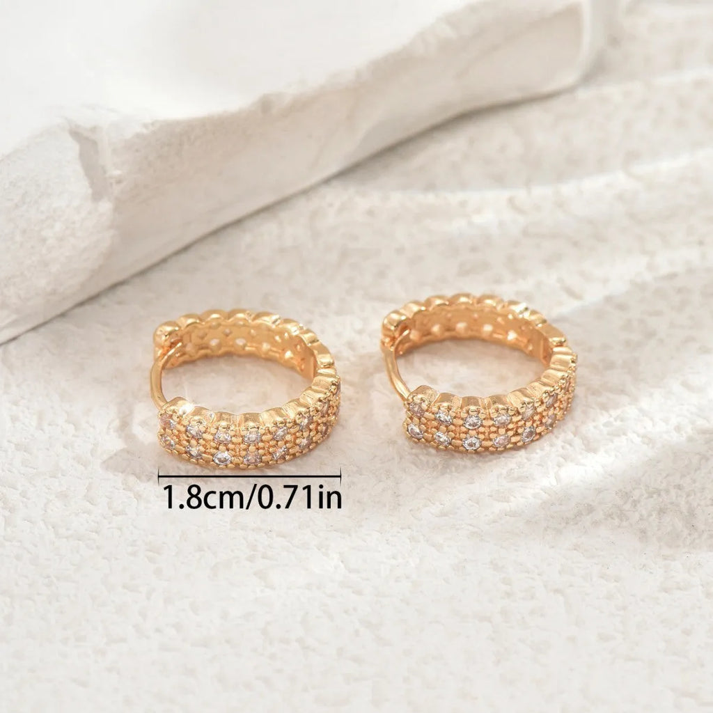 A pair of geometric pattern copper ear studs with round dot and ring details on a white background.