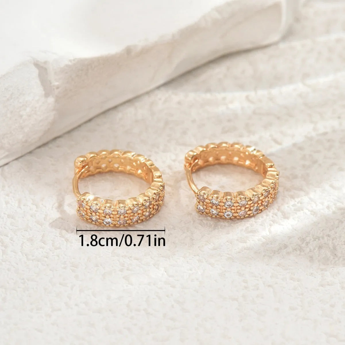 A pair of geometric pattern copper ear studs with round dot and ring details on a white background.