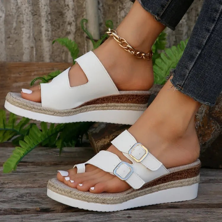 White patent leather wedge sandals with woven finger-fit straps and a peep toe design on a rubber sole.