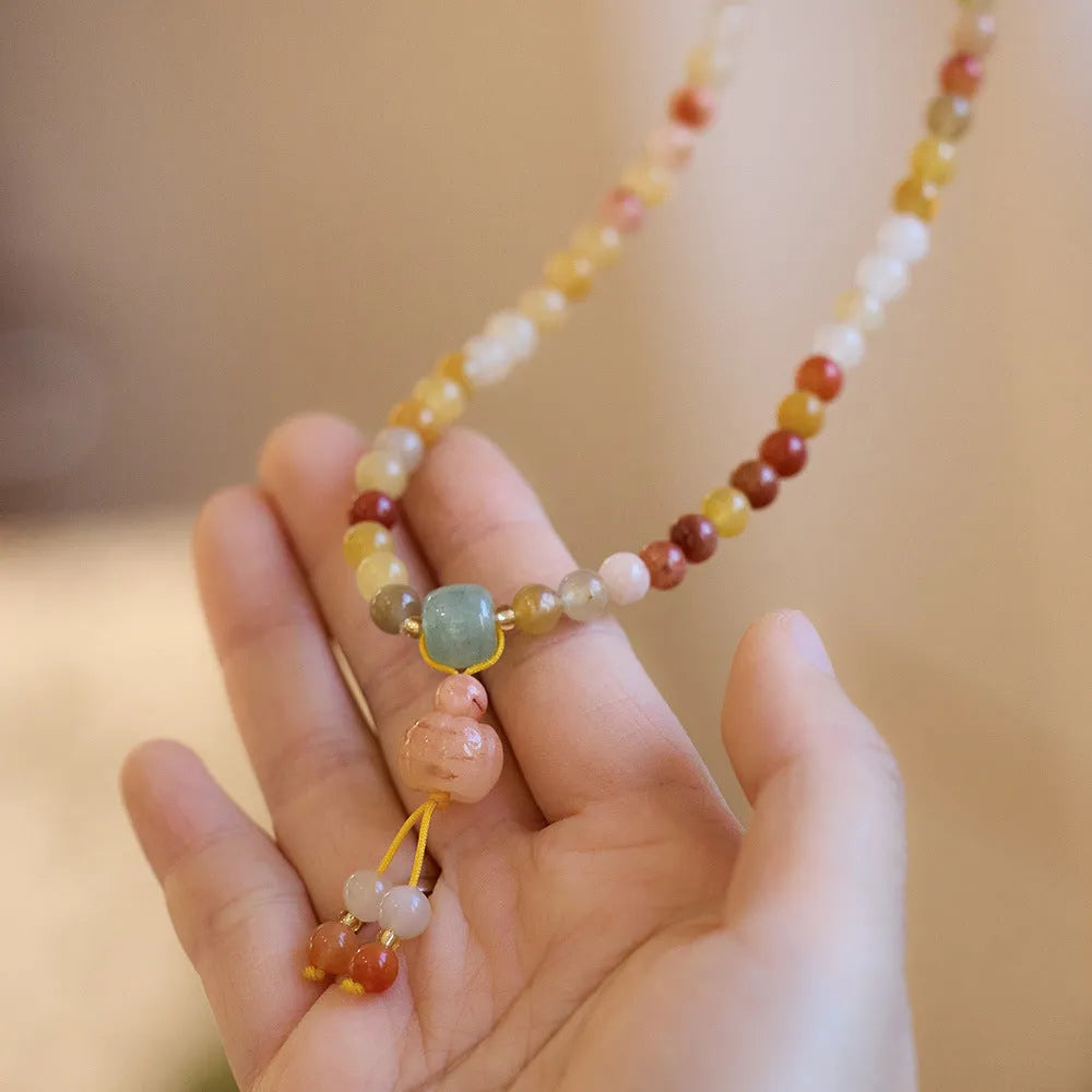 Handmade women's Jinsi Jade bracelet with three pumpkin beads and tassel on a wrist.