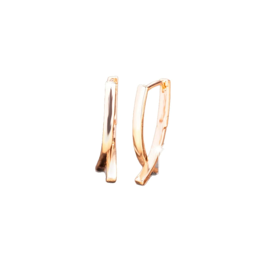 A pair of rose gold cross shaped earrings made from copper on a plain background.