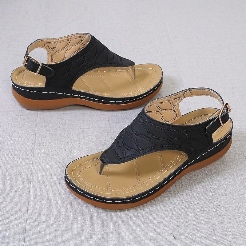 Women's black wedge heel sandals with an adjustable buckle back strap on a plain background.