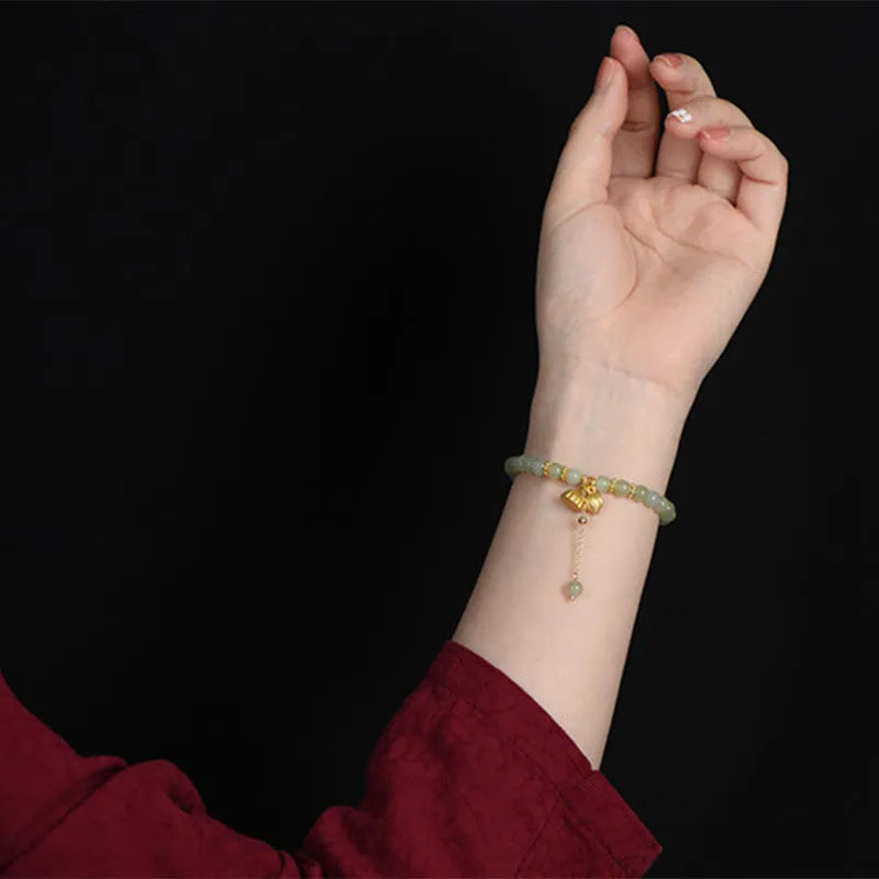 Natural Hetian jade bracelet with a carved Fu character charm on a wrist.