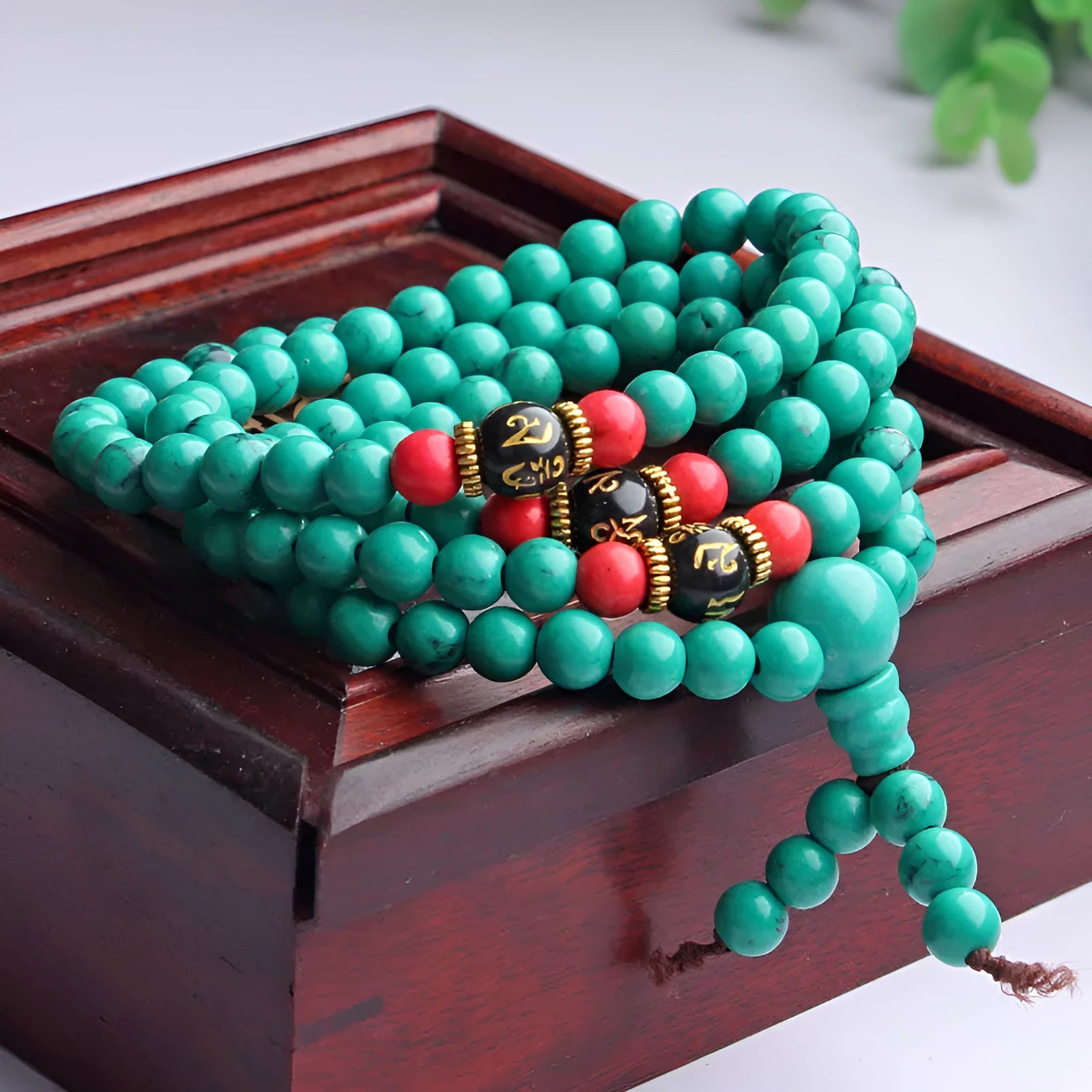 Multi-layer turquoise Tibetan bracelet with 108 round polished beads, shown in hand.