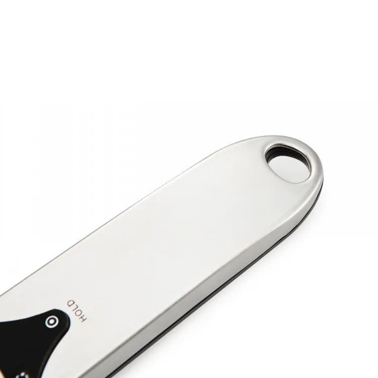 Digital smart measuring spoon with LCD screen showing weight, placed next to mixing bowl.