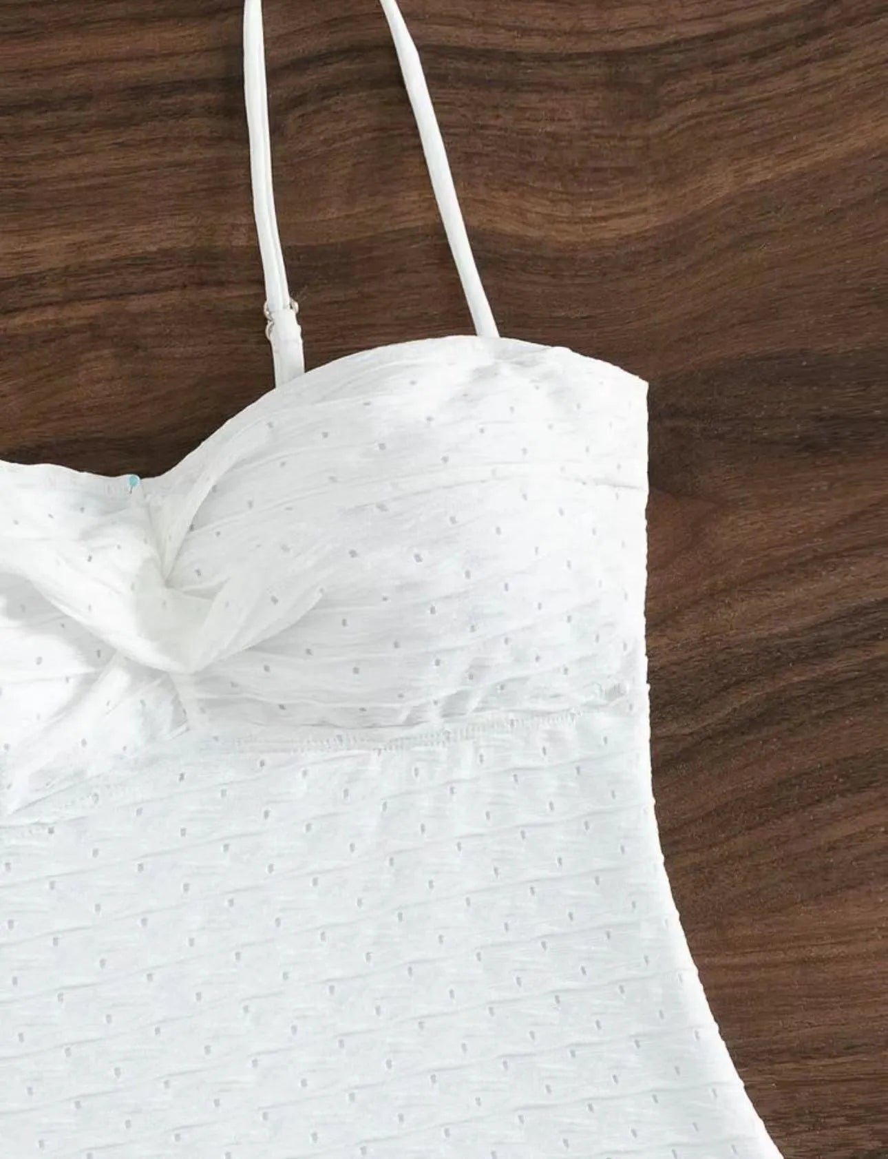 White one-piece swimsuit for women on a hanger, showing briefs style and sling detail.