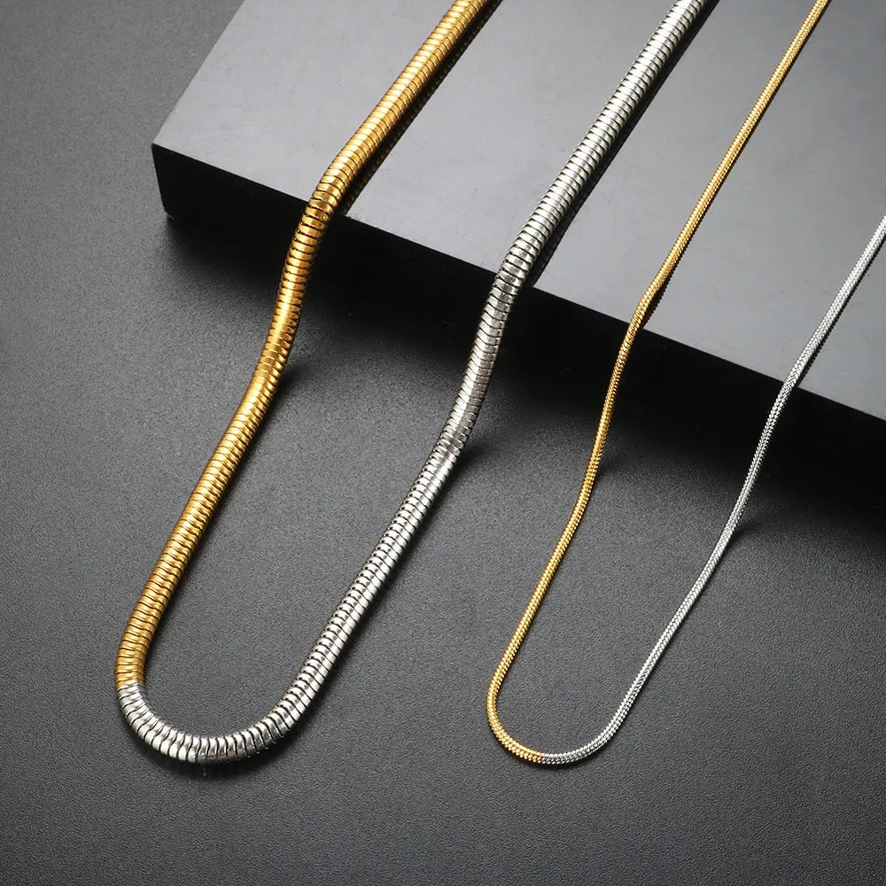 Cold golden 3mm wide stainless steel snake bones chain necklace on a flat surface.