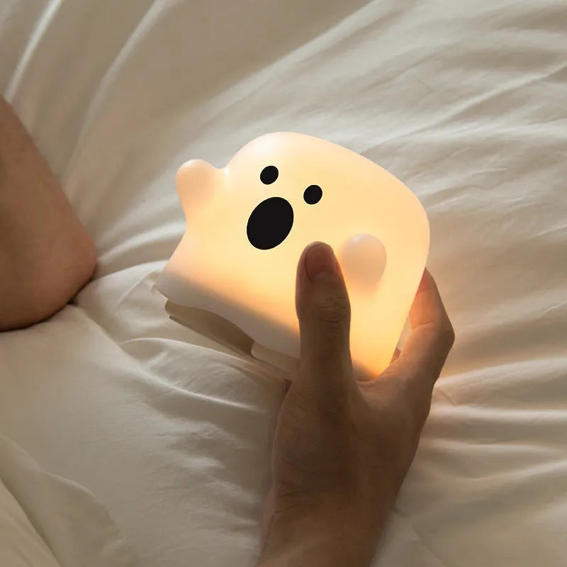 White portable LED touch sensor night light on a wooden bedside table.