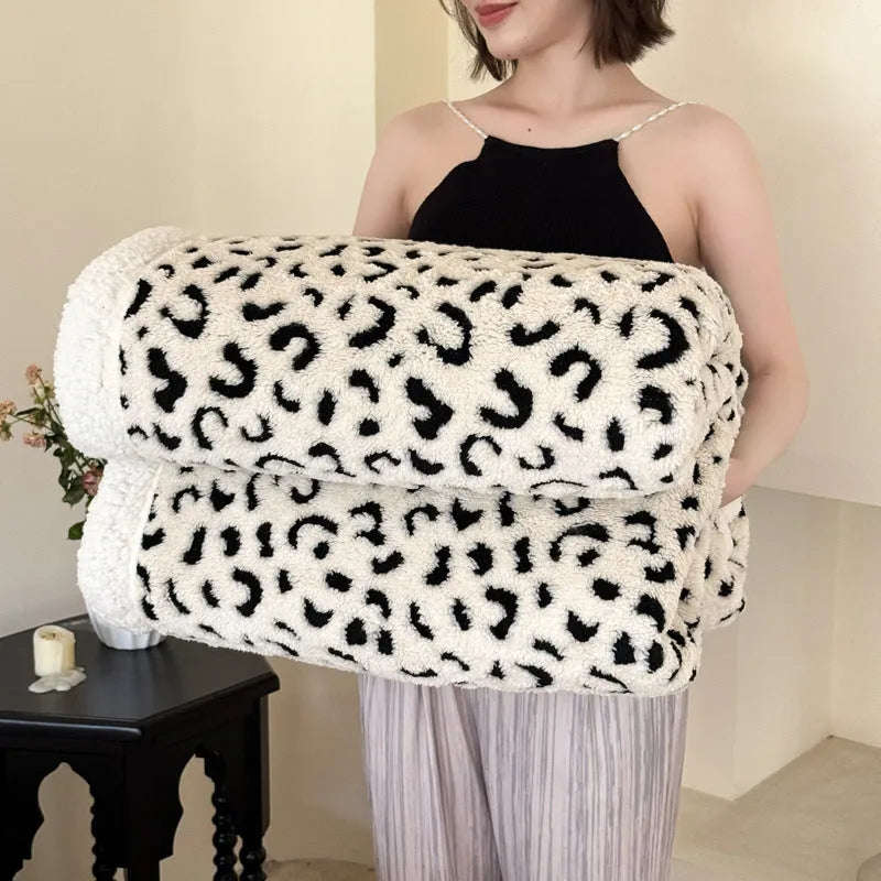 Double-layer taffeta blanket with reversible leopard jacquard print in camel colour, laid over a sofa.