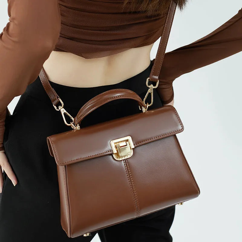 Women's black leather shoulder bag with a vachette clasp, showing its horizontal square shape and adjustable strap.