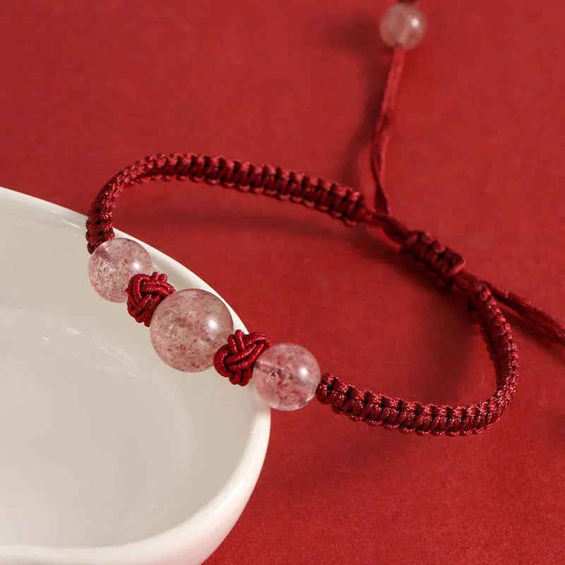 Woven red rope bracelet with spherical strawberry quartz or obsidian beads and an alloy clasp.