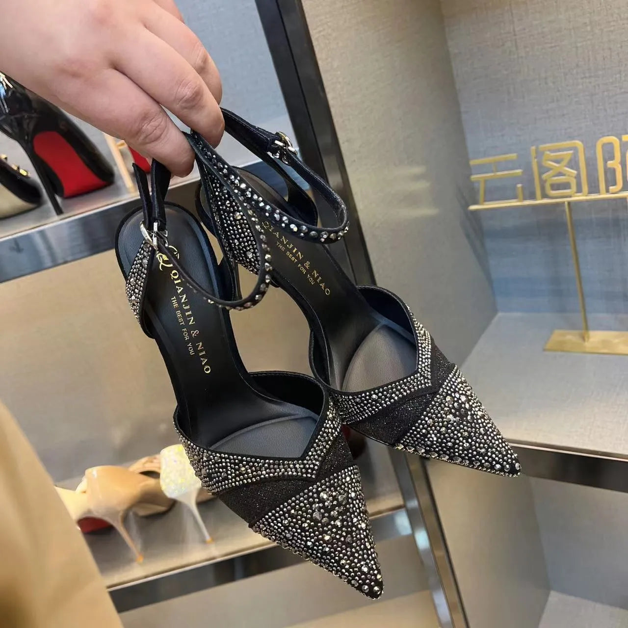 Women's black hollow high heel court shoe with red sole and pointed toe, stiletto heel.