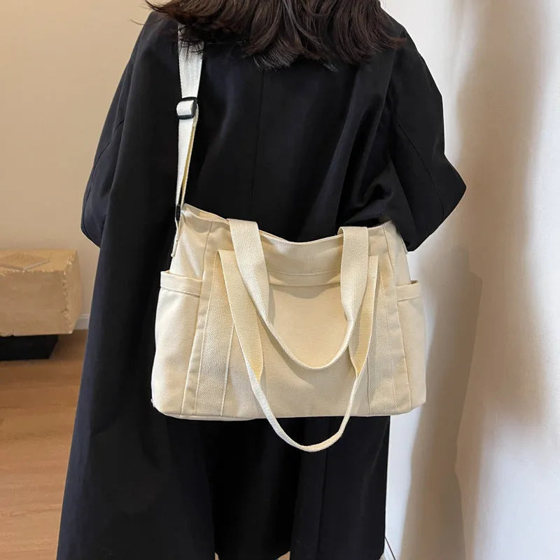 Polyester shoulder tote bag in solid colour with external sandwich pocket and internal phone pouch.