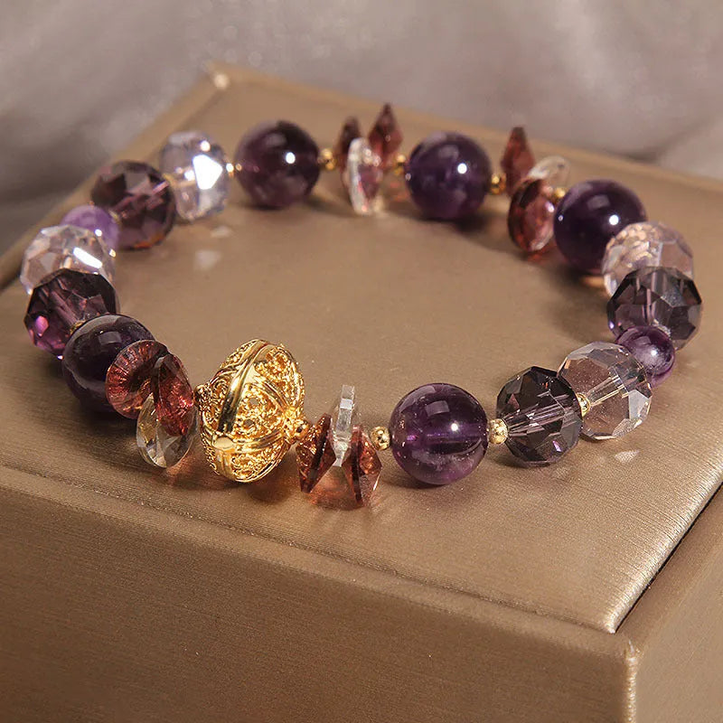 Purple crystal bracelet with pumpkin beads and a wind chimes charm on wrist.