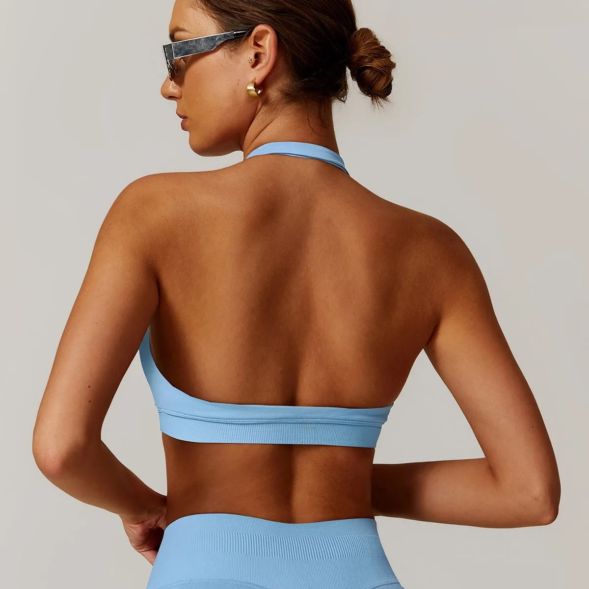 Women's black halter sports bra with hollow back and removable pads on a mannequin.