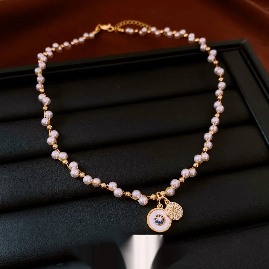 Gold electroplated necklace with round zircon-inlaid imitation pearl pendant on an adjustable clavicle chain.