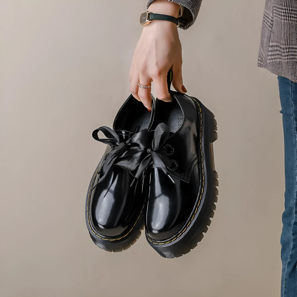 Women's black and white lace-up shoes with thick soles, ribbon details, and cross straps.