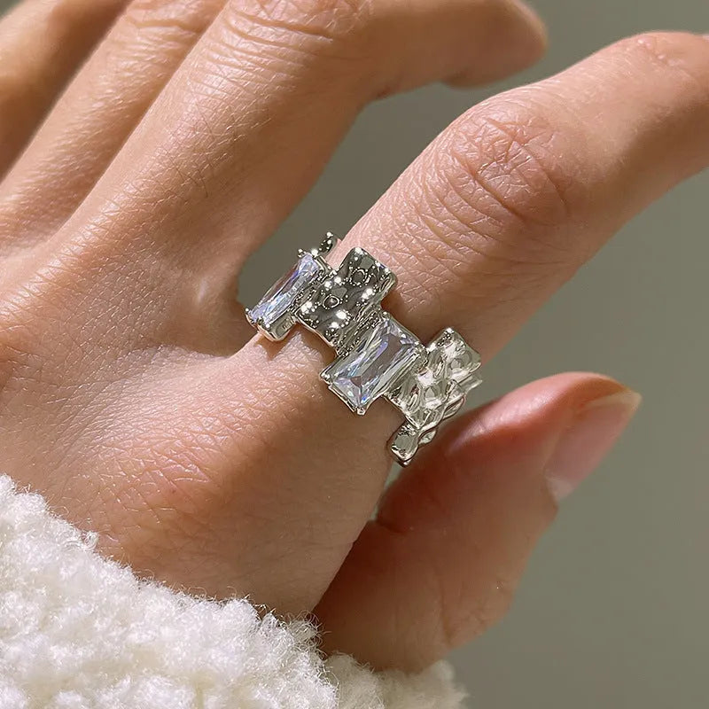 Silver geometric cross ring with open zircon stone setting.