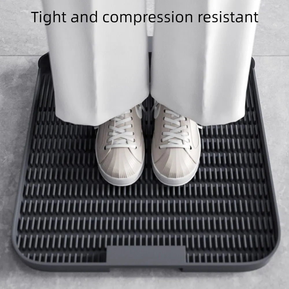 Large black cat litter pedal mat with textured grooves, placed next to a litter box.