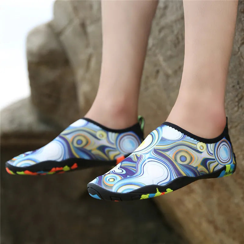 Blue Lycra beach wading shoes for men and women on a sandy shore.