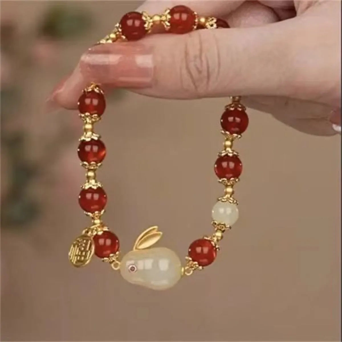 Handmade bracelet with glass beads, a rabbit charm, and a silver-coloured peace buckle on a white background.