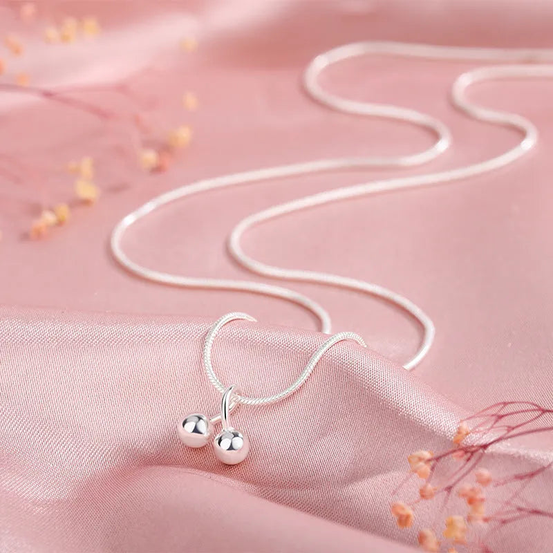 Silver cherry necklace for women with adjustable snake bone chain on a white background.
