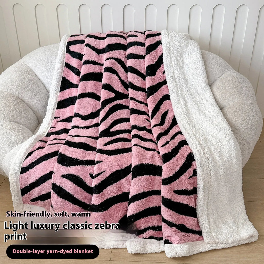 Double-layer taffeta blanket with reversible leopard jacquard print in camel colour, laid over a sofa.