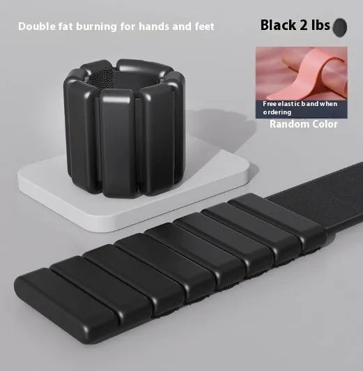 Silicone wrist weight bracelet with Velcro strap in black, blue, grey, or pink on a gym floor.