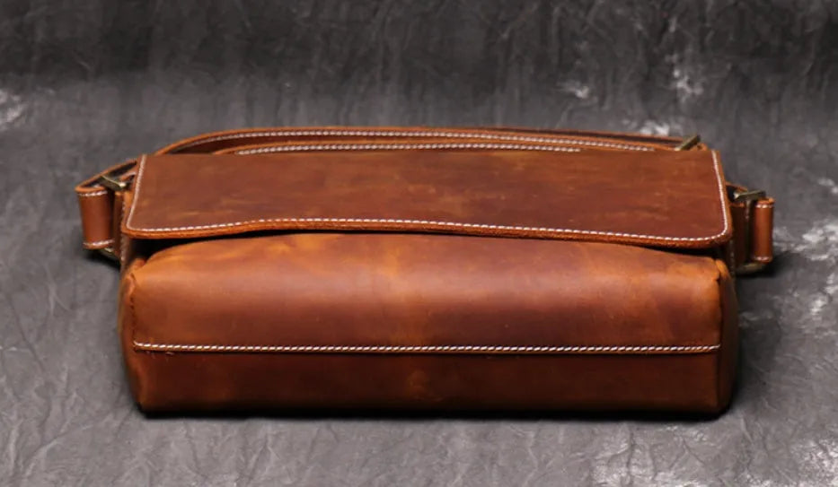 Vintage brown leather men's messenger bag with flap opening and adjustable shoulder strap.