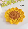 Hand-woven wool coaster with floral pattern on a wooden table.