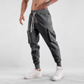 Men's loose grey cotton sports trousers with ankle ties and multiple pockets laid flat.