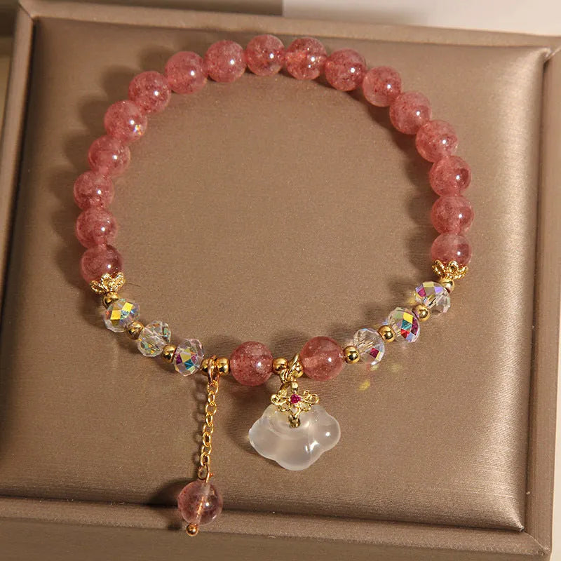 Women's bracelet with strawberry quartz and white agate beads and metal auspicious cloud charms on a white background.