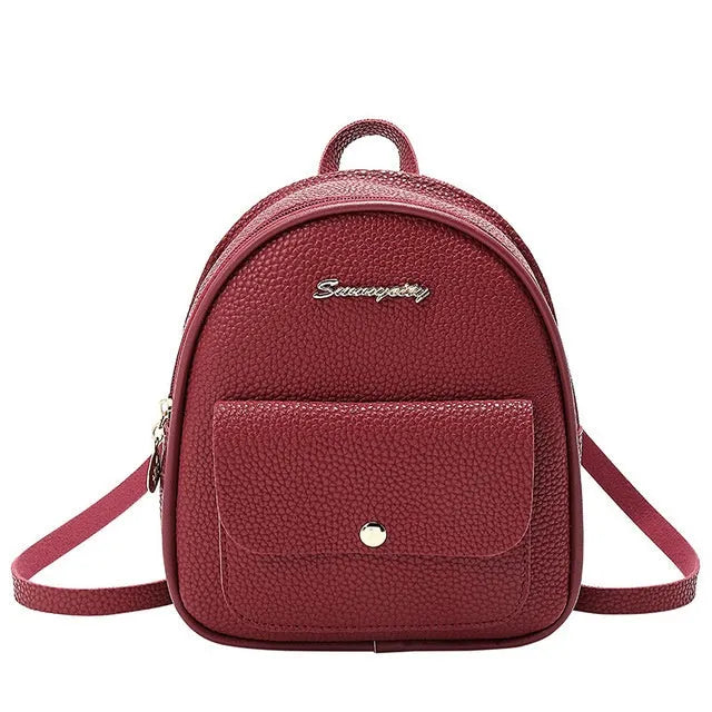 Small black PU women's backpack with zip, shown alongside a mobile phone for scale