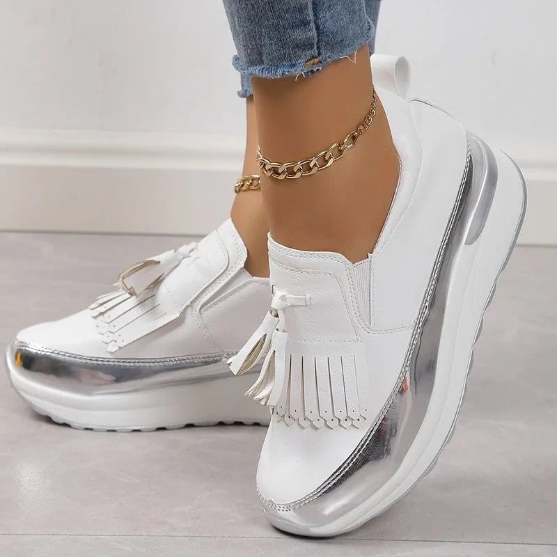 Women's black casual platform shoes with a tassel and distinctive muffin wedge heel on a white background.