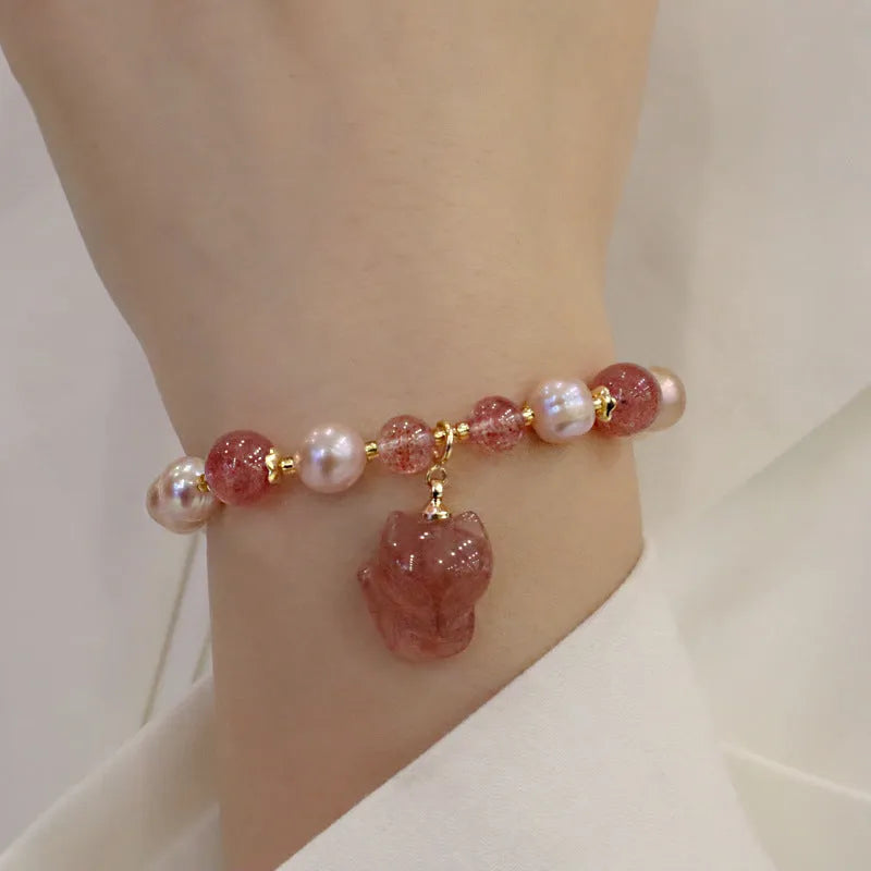 Women's light pink freshwater pearl bracelet with strawberry quartz beads and a small fox charm on an adjustable cord.