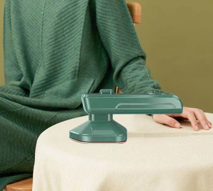 Dark green portable hand-held steam ironing machine with a ceramic panel.
