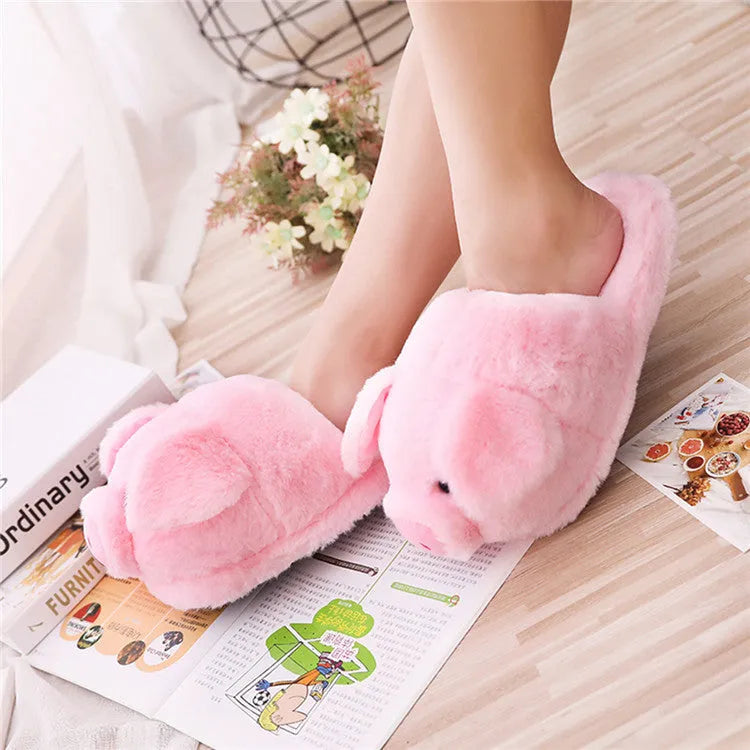 Pink pig-shaped plush floor slippers on a plain background.