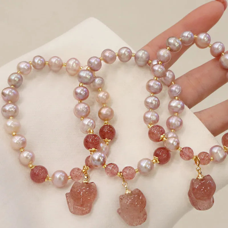 Women's light pink freshwater pearl bracelet with strawberry quartz beads and a small fox charm on an adjustable cord.