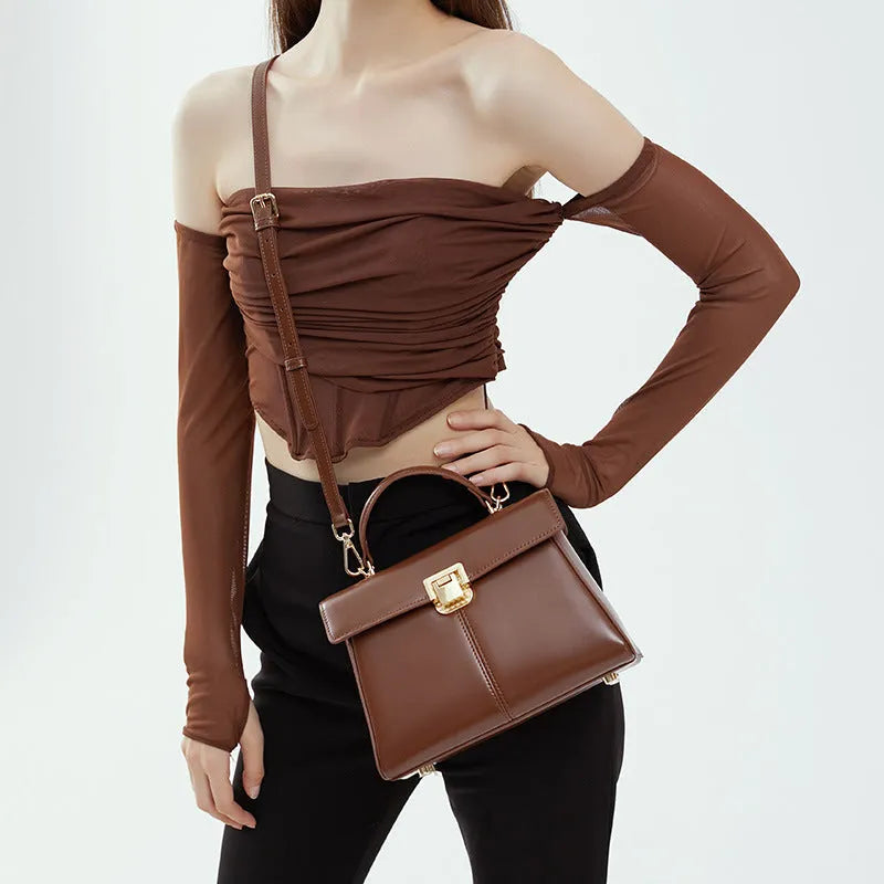 Women's black leather shoulder bag with a vachette clasp, showing its horizontal square shape and adjustable strap.